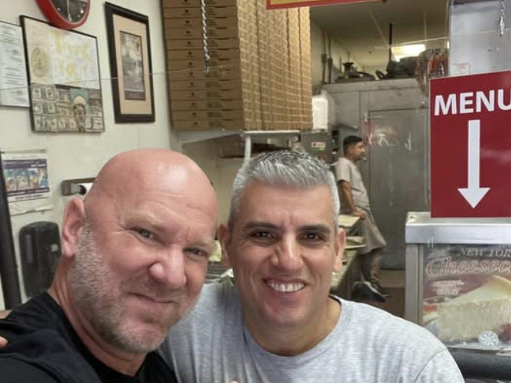A regular taking a selfie with Carlos, the owner of Pomodoro Pizza